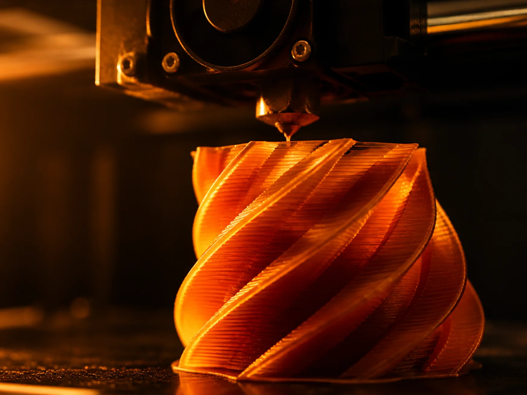 A 3D printer extruding warm orange filament in layered geometric shapes under dramatic lighting