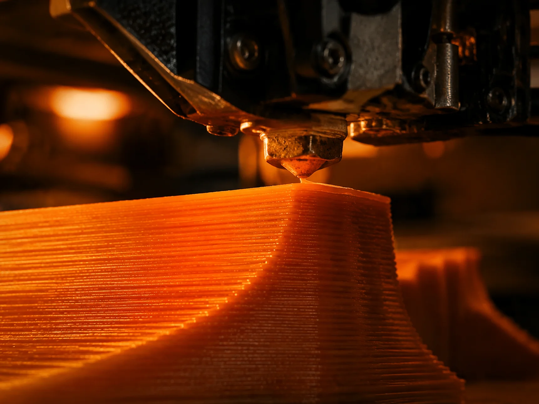 Macro view of a 3D printer nozzle extruding warm orange filament in precise layers